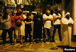 Men pray after a vehicle collided with pedestrians near a mosque in the Finsbury Park neighborhood of North London, Britain June 19, 2017. REUTERS/Neil Hall