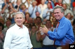 FILE - President George W. Bush, left, is introduced by his brother Florida Governor Jeb Bush, right, at a campaign rally, in Niceville, Florida, August 2004.