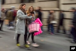 Shoppers carry their purchases as they walk along Fifth Avenue on Black Friday in New York, Nov. 25, 2016.