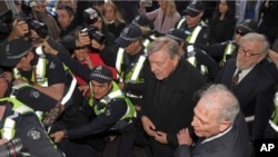 Cardinal George Pell, center right, is surrounded by police as he arrives at the Melbourne Magistrates Court in Melbourne, Australia, July 26, 2017.