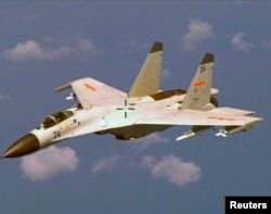 A Chinese J-11 fighter jet is seen flying near a U.S. Navy P-8 Poseidon about 215 km (135 miles) east of China's Hainan Island in this U.S. Department of Defense handout photo taken Aug. 19, 2014.