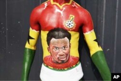 A Ghanaian football fan shows off his body painting, containing the image of star player Michael Essien