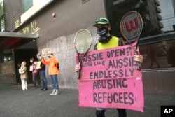 Pengunjuk rasa membentangkan spanduk di luar Park Hotel menyerukan pembebasan pengungsi yang ditahan di dalamnya di Melbourne, Australia, 8 Januari 2022. (Foto: AP)