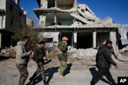 Russian and Syrian army soldiers gather at the last checkpoint before the front line with rebels, in Karam al-Tarab, east of Aleppo, Syria, Dec. 4, 2016.