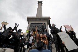 Activists, some wearing face coverings or face masks as a precautionary measure against COVID-19, hold placards as they attend a Black Lives Matter protest at Nelson's Column in Trafalgar Square in London on June 12, 2020.
