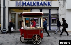 FILE - A street vendor sells roasted chestnuts in front of a branch of Halkbank in central Istanbul, Turkey.