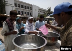 People receive drinking water from a volunteer at a stall, set up outside Jinnah Postgraduate Medical Center (JPMC) during intense hot weather in Karachi, Pakistan, June 23, 2015.