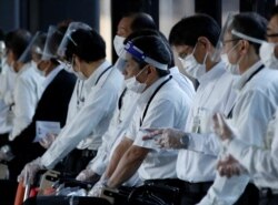 Staffs wearing face shields and masks wait for passengers who need wheelchairs at an arrival gate of Narita international airport on the first day of closed borders to prevent the spread of the new Omicron variant in Narita, east of Tokyo, Japan, Nov. 30,