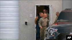 This frame grab from video provided by WPLG-TV shows FBI agents escorting Cesar Sayoc, in sleeveless shirt, in Miramar, Florida, on Oct. 26, 2018.