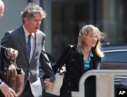 Actress Felicity Huffman arrives holding hands with her brother Moore Huffman Jr., left, at federal court in Boston, Massachusetts, April 3, 2019, to face charges in a nationwide college admissions bribery scandal.