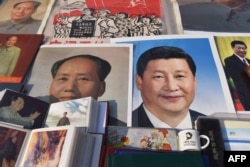 Posters of Chinese President Xi Jinping (R) and late communist leader Mao Zedong are seen at a market in Beijing on February 26, 2018.