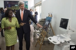 FILE - Then-U.S. Secretary of State John Kerry and entrepreneur Patricia Nzolantima point at an ultrasound machine during a tour of a Sustainable Investment in Sub-Saharan Africa medical supply store in Kinshasa, DRC, May 3, 2014.