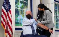 U.S. President Joe Biden holds up his sleeve to receive his coronavirus disease (COVID-19) booster vaccination in the Eisenhower Executive Office Building's South Court Auditorium at the White House in Washington, U.S., September 27, 2021