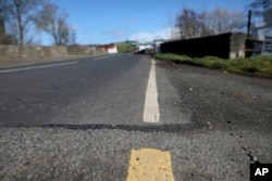 FILE - The Irish border, near the town of Middletown, Northern Ireland, March, 12, 2019. All that marks the border crossing is the change in paint and a cut in the tarmac, with white paint being in Northern Ireland and yellow paint used in the Republic of Ireland.