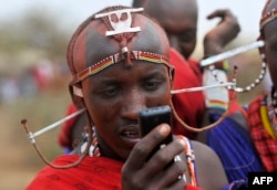 FILE - A Maasai moran uses a mobile phone in the village of Mbirukani in Kajiado, June 27, 2015.