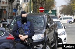 FILE - Belgium police officers secure the access during a police operation in Etterbeek, near Brussels, Belgium, April 9, 2016.