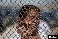 A Mexican migrant talks to a family member through the border fence between Ciudad Juarez and El Paso, United States, after a bi-national Mass in support of migrants in Ciudad Juarez, Mexico, Feb.15, 2016.