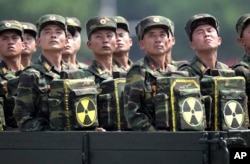 FILE - North Korean soldiers turn and look towards their leader Kim Jong Un from a military parade vehicle as they carry packs marked with the nuclear symbol during a ceremony marking the 60th anniversary of the Korean War armistice in Pyongyang, North Korea.