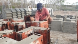 Seorang tukang sedang membuka cetakan panel beton p3 yang digunakan sebagai siku sambungan untuk kebutuhan hunian risha. (Foto: VOA/Yoanes Litha)