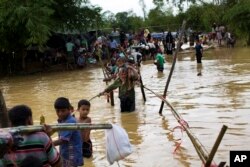 Rohingya Muslims cross a flooded area to find an alternate shelter after their camp was inundated with rainwater near Balukhali refugee camp, Bangladesh, Sept. 19, 2017.