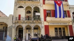 Special forces police patrol the streets as they drive past a large Cuban flag hanging from the facade of a building, in Havana, Cuba, Wednesday, July 21, 2021. (AP Photo/Eliana Aponte)