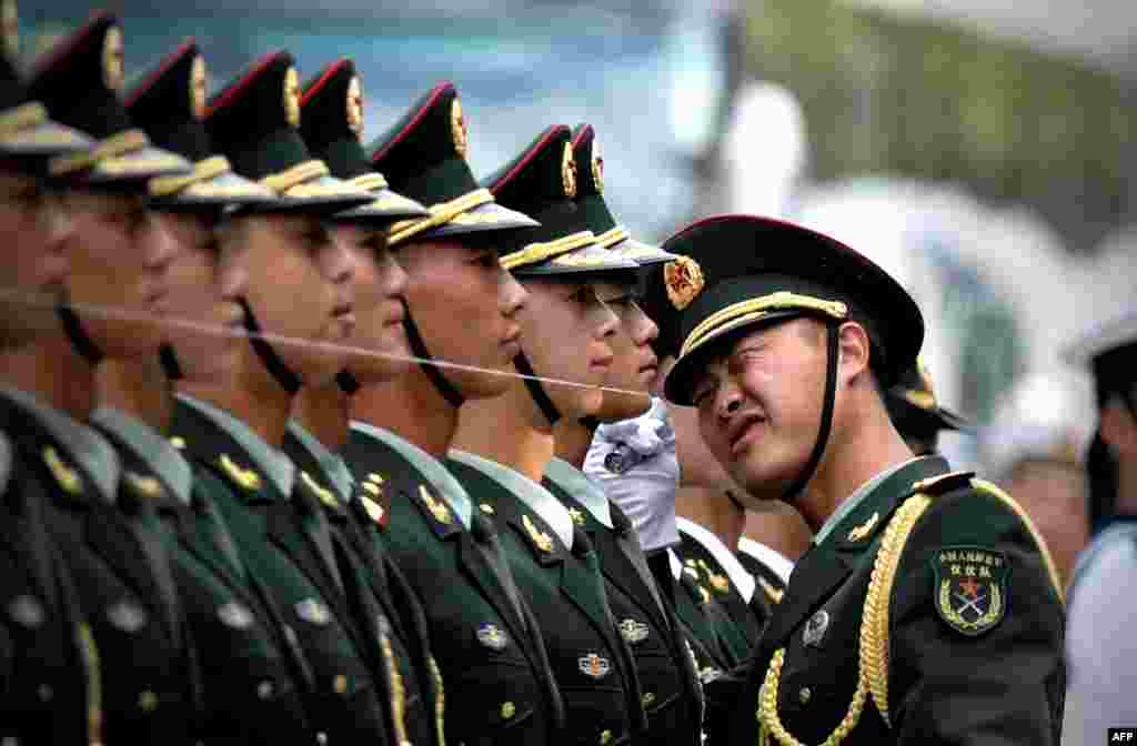 Regu penjaga kehormatan China mempersiapkan diri untuk menyambut kedatangan Presiden Myanmar ( yang juga dikenal sebagai Burma)&nbsp; U Thein Sein dan Presiden China Xi Jinping dalam upacara kehormatan di luar balai kota rakyat di Beijing. Sebuah benang direntangkan untuk memastikan mereka berdiri dalam garis lurus. &nbsp; 