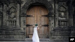 FILE - On her wedding day, a Filipino bride fixes her gown before entering a Catholic church in Manila, Philippines. (AP Photo/Aaron Favila)