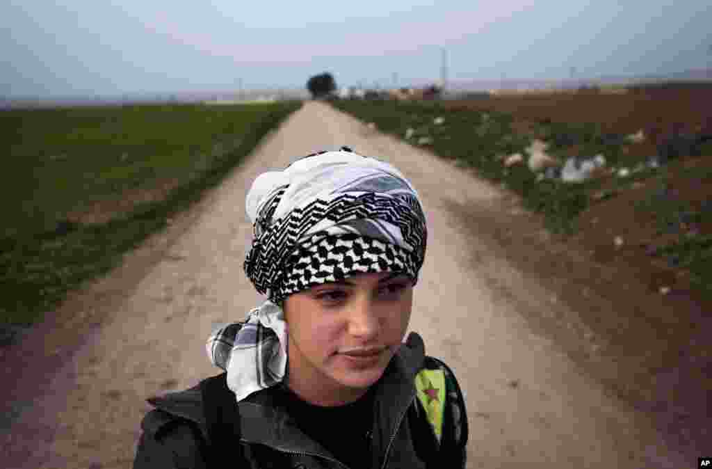 A member of the Popular Protection Units stands guard at a check point near Qamishli, Syria, March 3, 2013.
