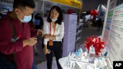 A visitor wearing a face mask looks at a model of a coronavirus and boxes for COVID-19 vaccines at a display by Chinese pharmaceutical firm Sinopharm at the China International Fair for Trade in Services (CIFTIS) in Beijing, Saturday, Sept. 5, 2020…