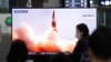 FILE - People watch a TV showing an image of North Korea's new guided missile during a news program at the Suseo Railway Station in Seoul, South Korea, March 26, 2021. 
