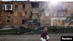 Seorang perempuan berjalan melewati sebuah bangunan yang rusak akibat serangan rudal, saat invasi Rusia ke Ukraina berlanjut, di wilayah Donbas timur Bakhmut, Ukraina, 1 November 2022. (REUTERS/Clodagh Kilcoyne)