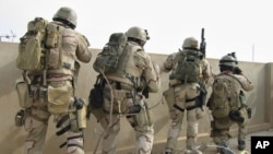 FILE - A team of U.S. Navy SEALs battles insurgents from a rooftop in Ramadi, Iraq, April 2006. Special Operations Chief Edward Gallagher plans to plead not guilty Friday to allegations of shooting at Iraqi civilians and killing an Islamic State teen.