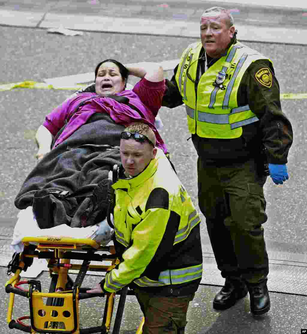 Petugas medis membawa seorang korban yang terluka akibat ledakan bom pada Marathon Boston (15/4). (AP/Charles Krupa)