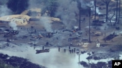 Smoke rises from an illegal oil refinery in Ogoniland, outside Port Harcourt, in Nigeria's Delta region in this Thursday, March 24, 2011 photo. Shell flew journalists in a helicopter over a cleared area in the delta where locals ran makeshift refineries turning stolen crude tapped from pipelines into diesel and kerosene. The company blamed nearly all of its oil spills in 2009 on sabotage from thieves and militants. Environmentalists and community activists routinely blame Shell for the spills, pointing at the company's aging pipelines and poor cleanup efforts. (AP Photo/Sunday Alamba)