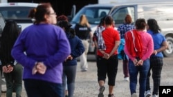 Government agents lead suspects in custody toward a restroom during an immigration sting at Corso's Flower and Garden Center in Castalia, Ohio, June 5, 2018.