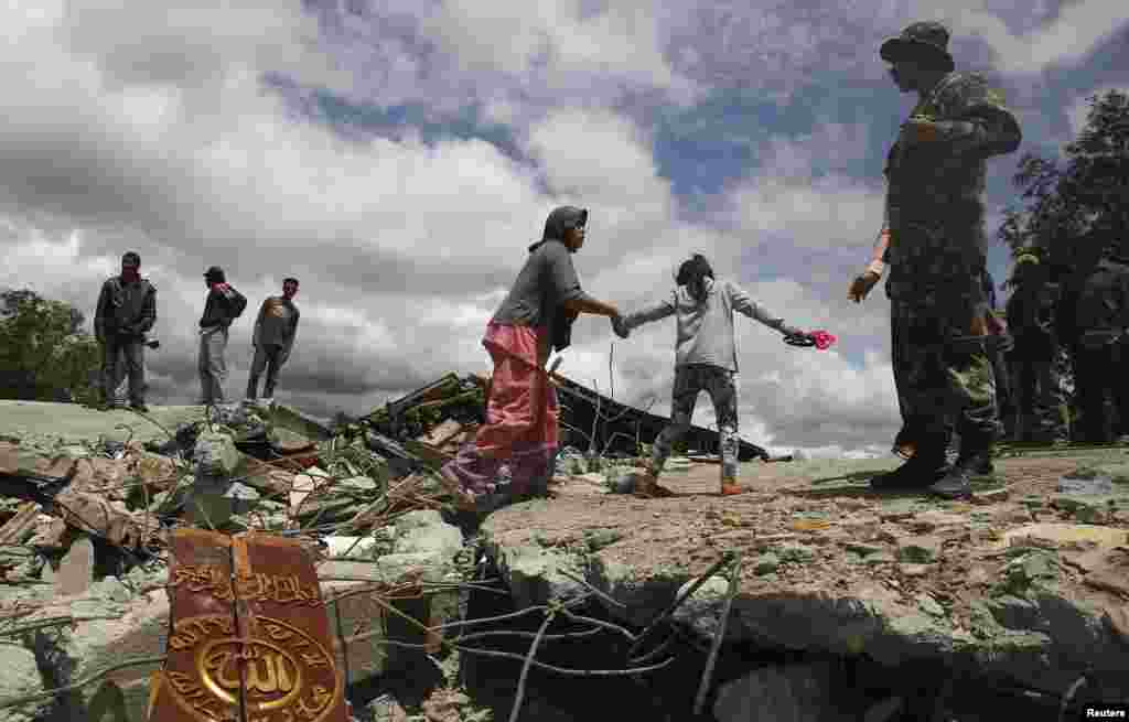 Residents walk on a collapsed mosque in Blang Mancung village after a 6.1 magnitude earthquake hit Aceh province, July 3, 2013. 