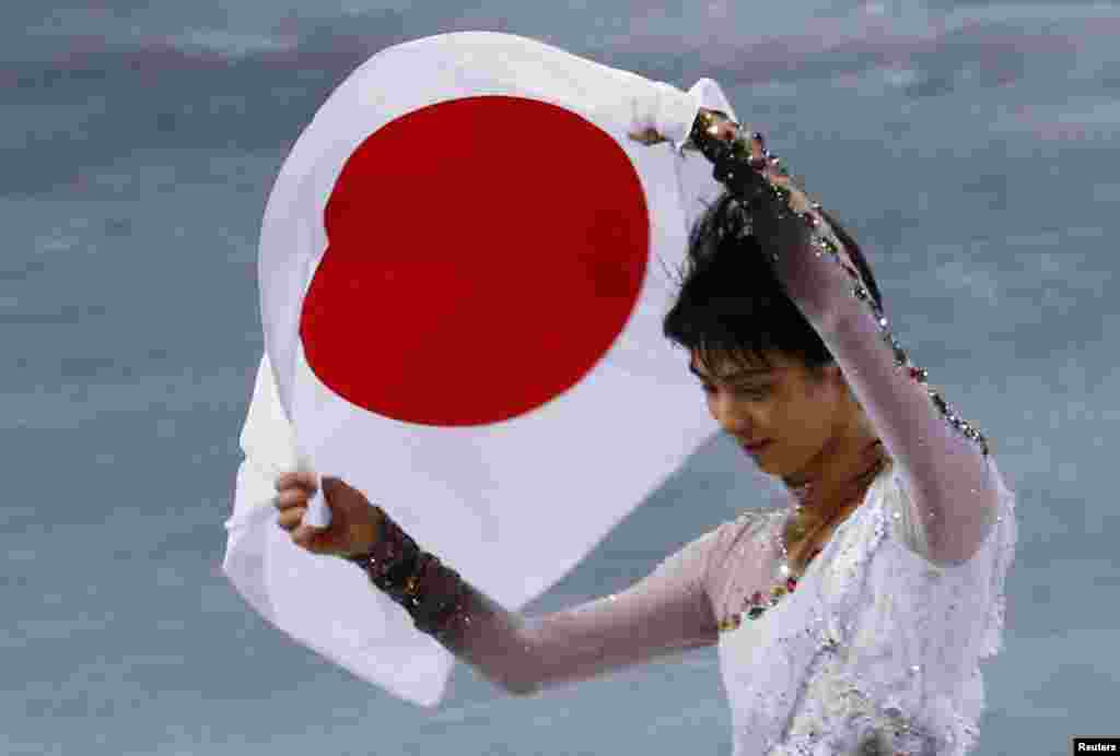 Japan's Yuzuru Hanyu carries the Japanese flag after winning gold in the men's free skating event at the 2014 Winter Olympics, February 14, 2014. 