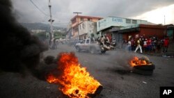 FILE - Police drive past burning tires lit by anti-government protestors, in Port-au-Prince, Haiti, Oct. 4, 2019.