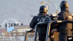 Para narapidana berdiri di atas atap penjara Topo Chico sementara para polisi berjaga-jaga setelah perkelahian pecah sekitar tengah malam di Monterrey, Meksiko, 11 Februari 2016. 