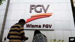 A couple talks outside FGV Holdings Berhad, one of Malaysia's largest palm oil companies, in Kuala Lumpur, Thursday, Oct. 1, 2020. Malaysian palm oil producer FGV Holdings Berhad vowed Thursday to “clear its name” after the U.S. banned imports of…