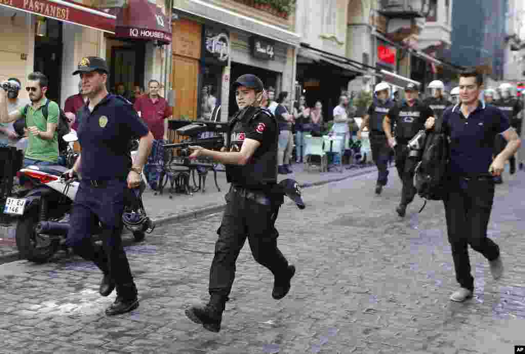 Polisi Turki, salah satunya memegang senapan peluru karet, berlari membubarkan peserta pawai Gay Pride di Istanbul (28/6). ​(AP/Emrah Gurel)