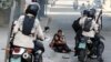 FILE – Venezuelan security forces pause near opposition supporters affected by tear gas during a demonstration in Caracas, July 9. A new Amnesty International report condemns 'illegal home raids' against suspected dissidents. 