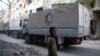 FILE - A boy stands as an aid convoy of Syrian Arab Red Crescent drives through the town of Douma, Eastern Ghouta, near Damascus, Syria, March 5, 2018.