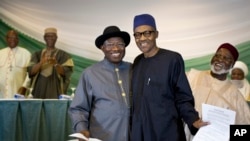 Nigeria's President Goodluck Jonathan, center-left, and opposition candidate Gen. Muhammadu Buhari, center-right, hug and shake hands after signing a renewal of their pledge to hold peaceful "free, fair, and credible" elections, at a hotel in Abuja.