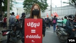Baifern Benjama, a pro-democracy protester, holds a sign reading "Reform = make it better," at a Bangkok street protest. (Vijitra Duangdee/VOA)