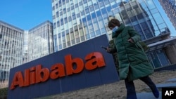 A woman wearing a face mask runs past the offices of Chinese e-commerce firm Alibaba in Beijing on Dec. 13, 2021. (AP Photo/Andy Wong)