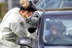 FILE - Medical staff test a shopper in her car who volunteered at a pop-up community COVID-19 testing station at a supermarket carpark in Christchurch, New Zealand, Friday, April 17, 2020.