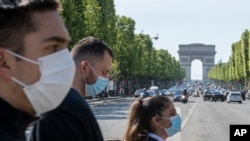 People wear face masks to help curb the spread of the coronavirus cross the Champs Elysees avenue in Paris, May 16, 2020, as France gradually lifts its Covid-19 lockdown.