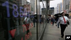 A man walk past a bank electronic board showing the Hong Kong share index at Hong Kong Stock Exchange Thursday, Feb. 11, 2015.