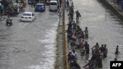 Ljudi prelaze poplavljenu ulicu nakon obilnih padavina u Karačiju, Pakistan, 23. septembar 2021. (Foto: Asif HASSAN / AFP)